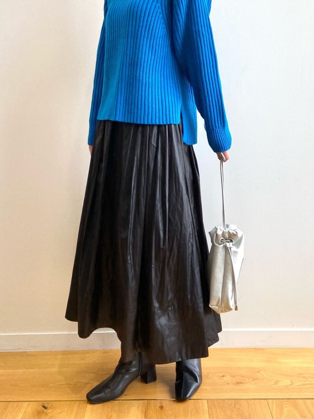 ブルー系のニット/セーター、ブラック系のスカート、ブラック系のブーツを着用したレディースの秋コーディネートの8枚目の写真