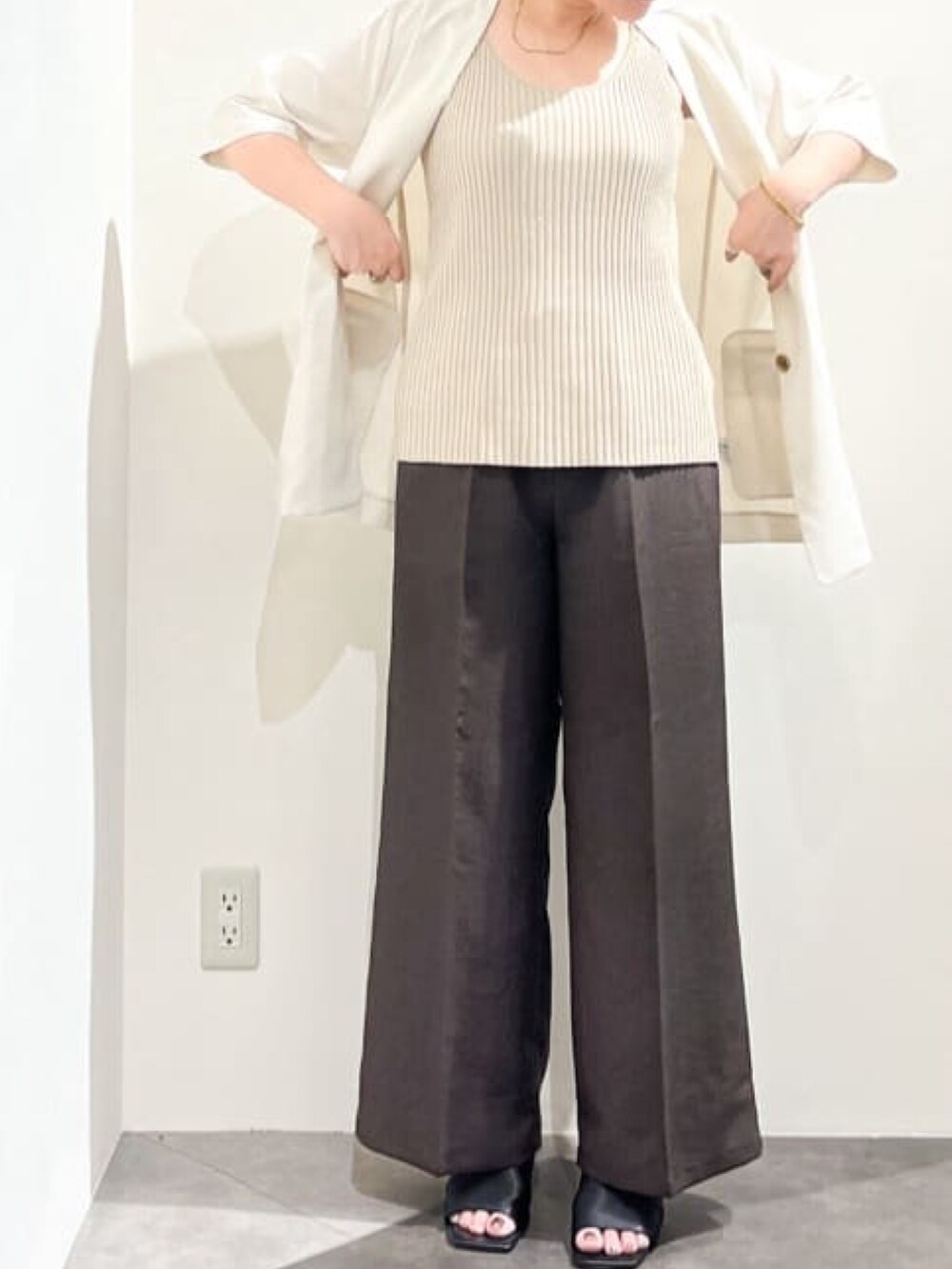 ベージュ系のノーカラージャケット、ベージュ系のニット/セーター、ブラック系のショルダーバッグを着用したレディースの夏コーディネートの6枚目の写真