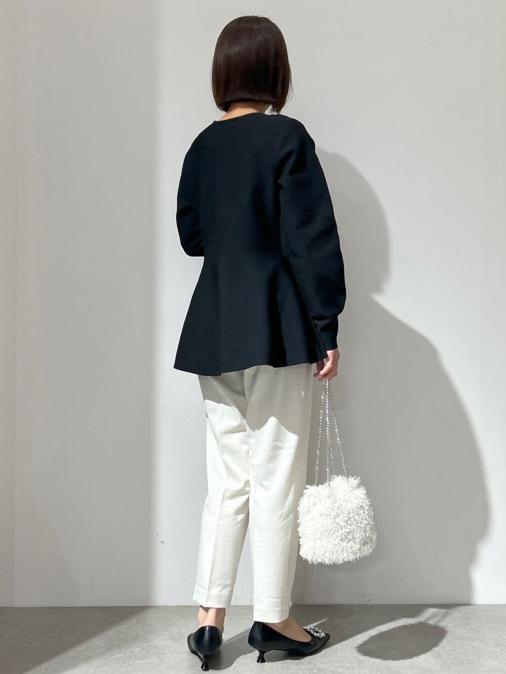 ブラック系のニット/セーター、ホワイト系のその他パンツ、ホワイト系のショルダーバッグを着用したレディースの冬コーディネートの3枚目の写真