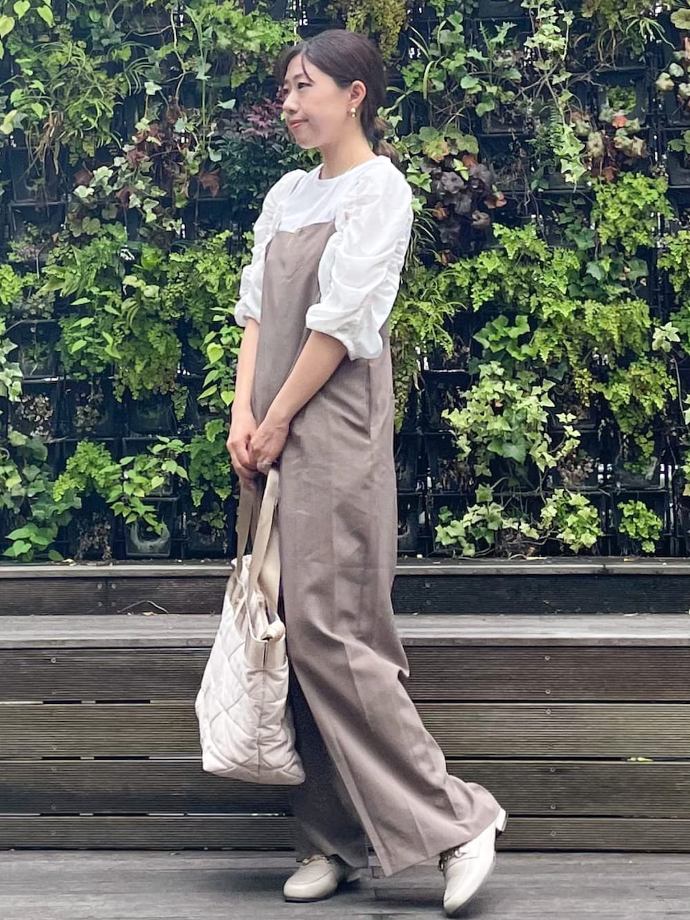 ベージュ系のトートバッグ、ベージュ系のドレスシューズ、ブラウン系のサロペット/オーバーオールを着用したレディースの秋コーディネートの3枚目の写真