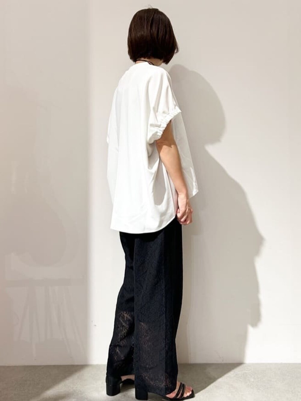 ホワイト系のTシャツ/カットソー、ブラック系のその他パンツ、ブラック系のサンダルを着用したレディースの春コーディネートの4枚目の写真