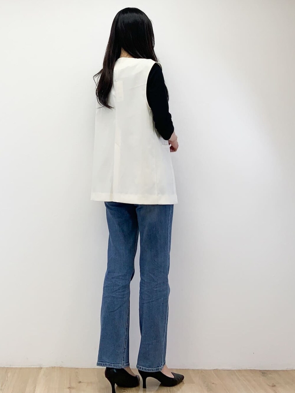 ホワイト系のベスト、ブラック系のTシャツ/カットソー、ブルー系のデニムパンツを着用したレディースの秋コーディネートの6枚目の写真