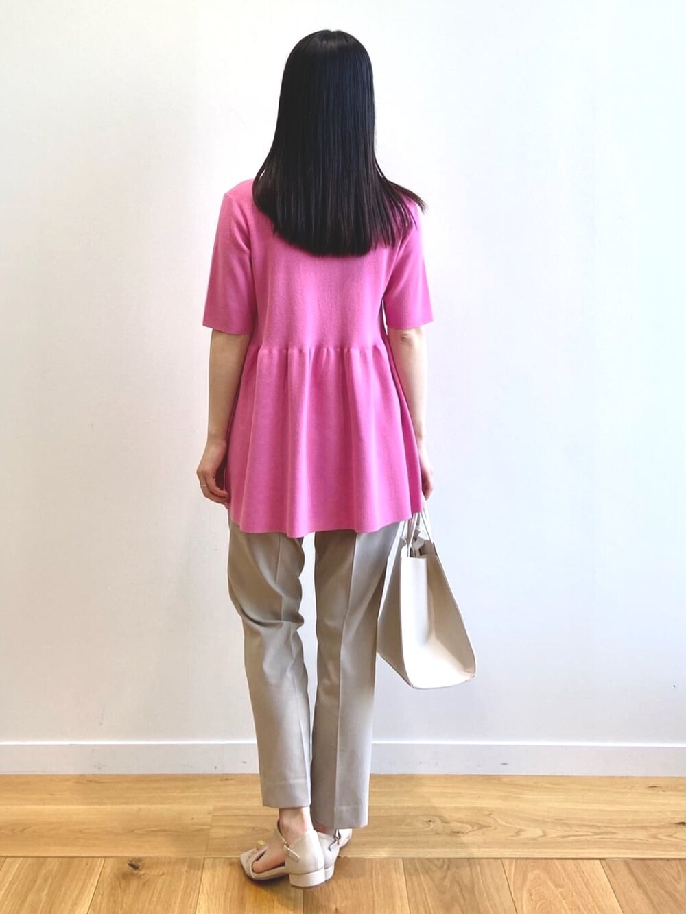 ピンク系のニット/セーター、ベージュ系のその他パンツ、ホワイト系のトートバッグを着用したレディースの夏コーディネートの3枚目の写真