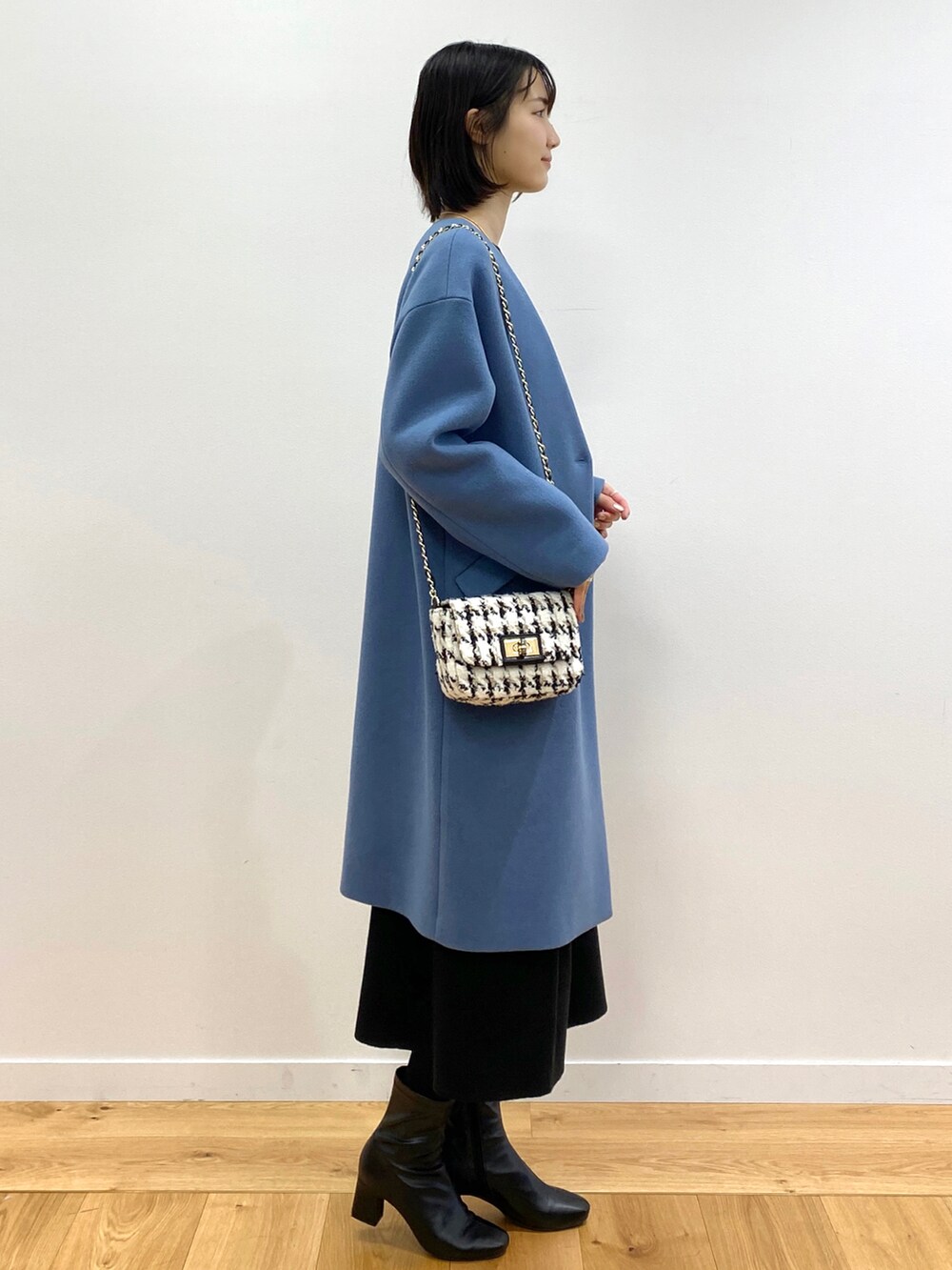 ブラック系のニット/セーター、ブラック系のスカート、ブルー系のノーカラーコートを着用したレディースの冬コーディネートの2枚目の写真