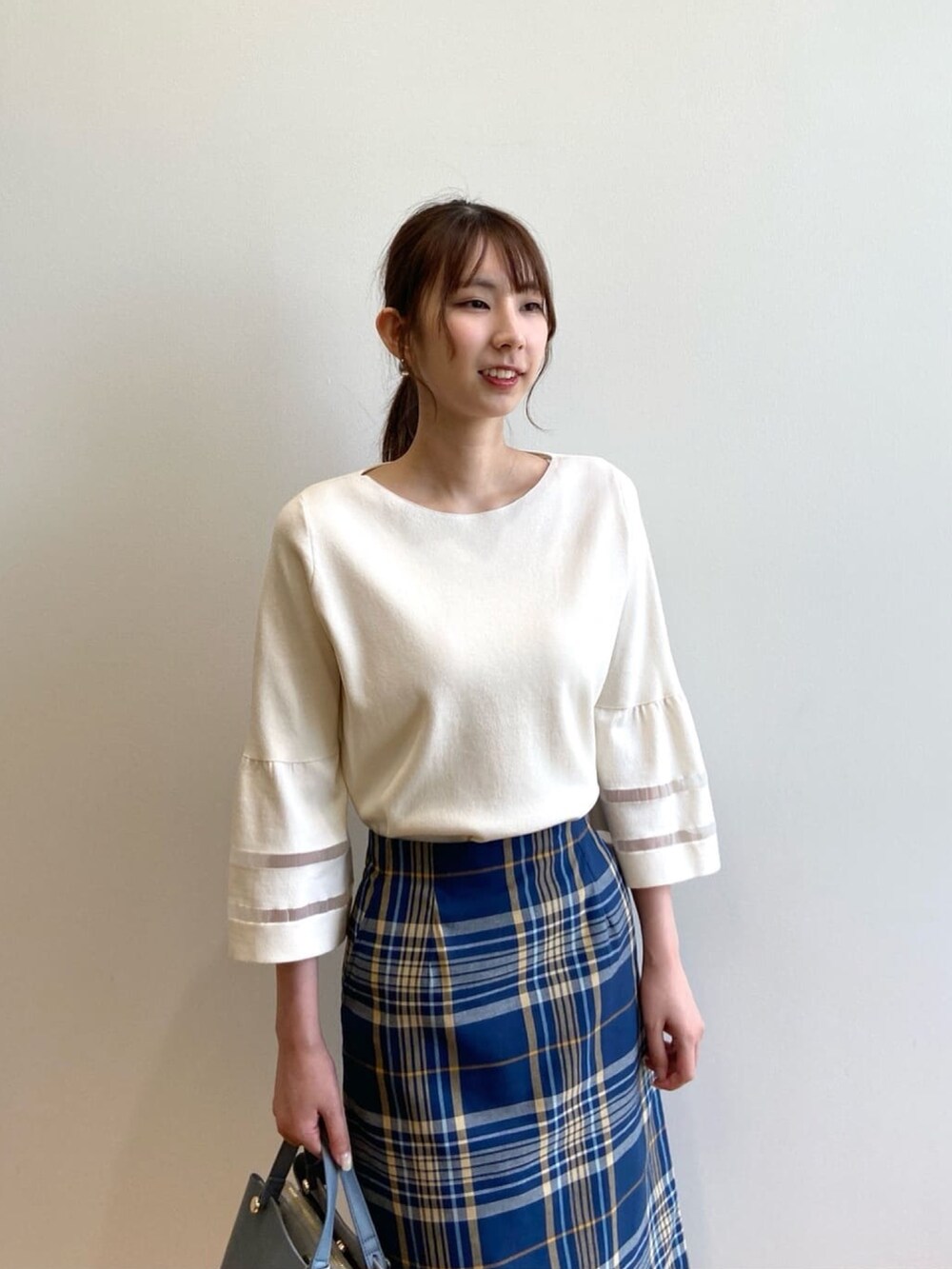 ホワイト系のニット/セーター、ブルー系のスカート、ベージュ系のパンプスを着用したレディースの夏コーディネートの8枚目の写真