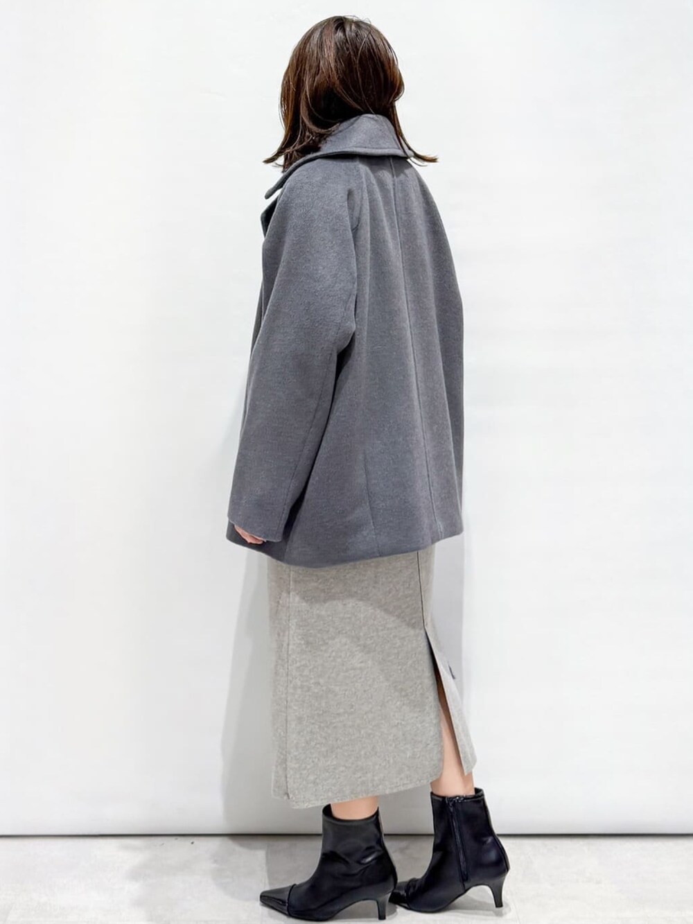 ブラック系のニット/セーター、グレー系のピーコート、グレー系のショルダーバッグを着用したレディースの秋コーディネートの5枚目の写真