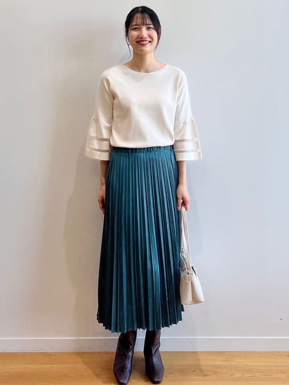 ブラウン系のブーツ、ホワイト系のニット/セーター、ブルー系のスカートを着用したレディースの夏コーディネートの2枚目の写真