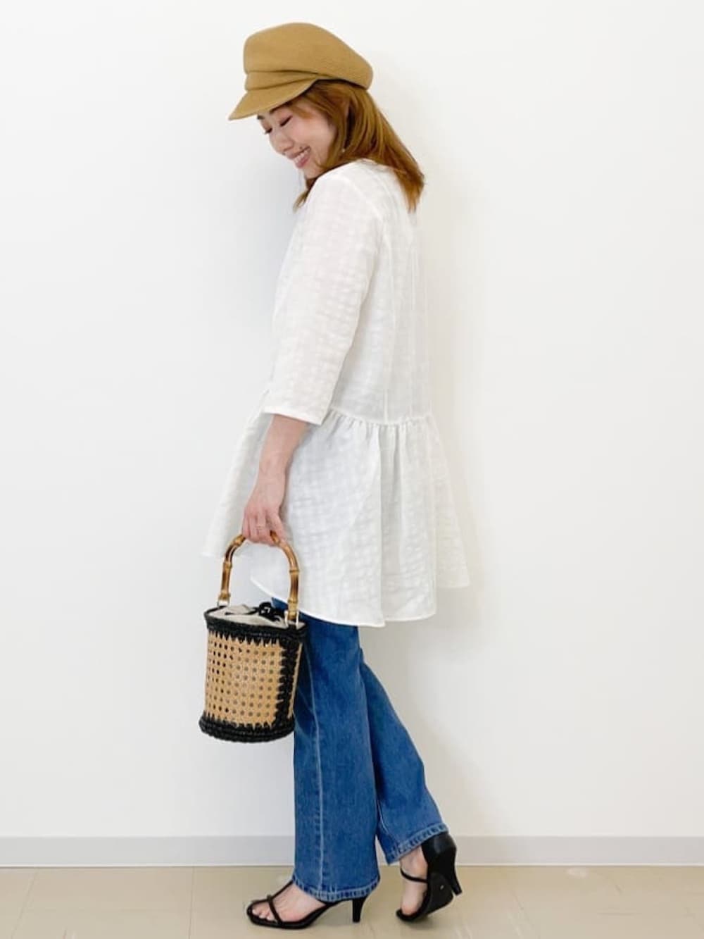 ブラック系のサンダル、ブラック系のトートバッグ、ホワイト系のチュニックを着用したレディースの夏コーディネートの2枚目の写真