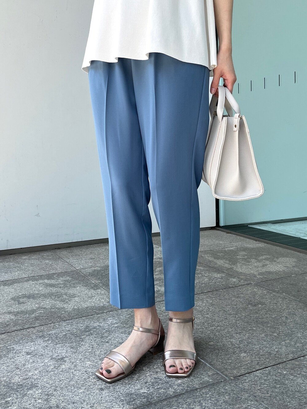 ホワイト系のニット/セーター、ブルー系のその他パンツ、ゴールド系のサンダルを着用したレディースの春コーディネートの6枚目の写真