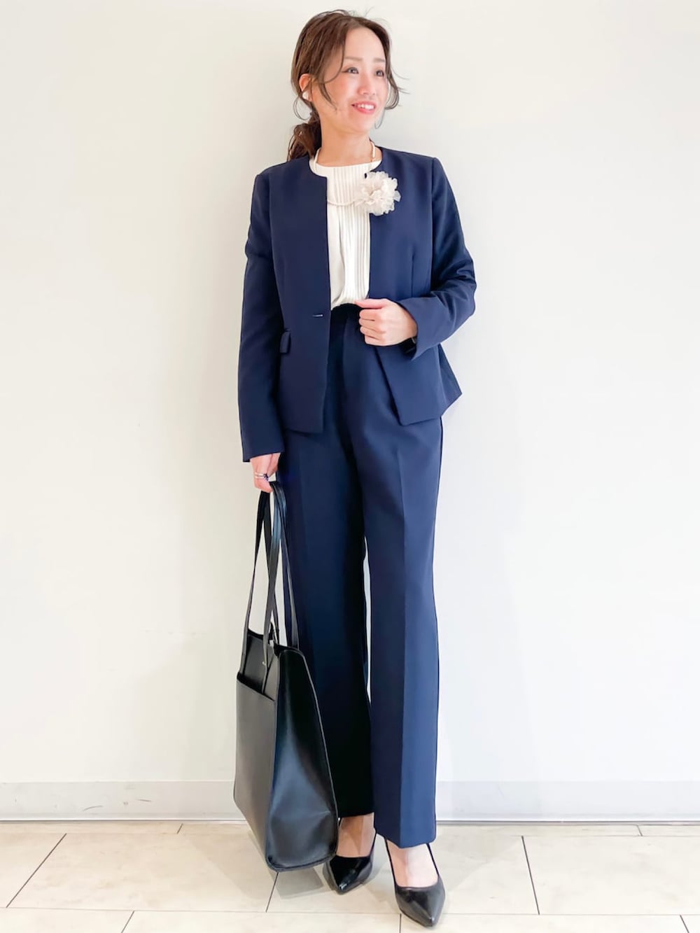 ブラック系のパンプス、ベージュ系のトレンチコート、ブルー系のスーツパンツを着用したレディースの春コーディネートの2枚目の写真