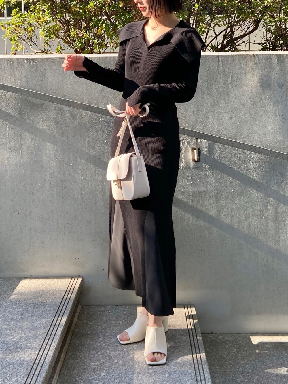グリーン系のカーディガン/ボレロ、ブラック系のワンピース、ホワイト系のサンダルを着用したレディースの春コーディネートの2枚目の写真