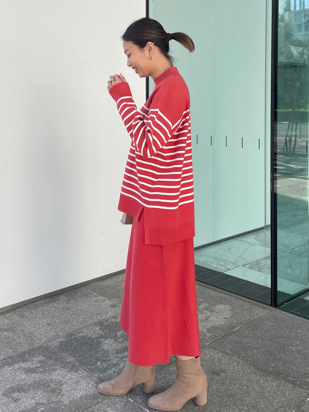 レッド系のニット/セーター、レッド系のスカート、ベージュ系のブーツを着用したレディースの冬コーディネートの2枚目の写真