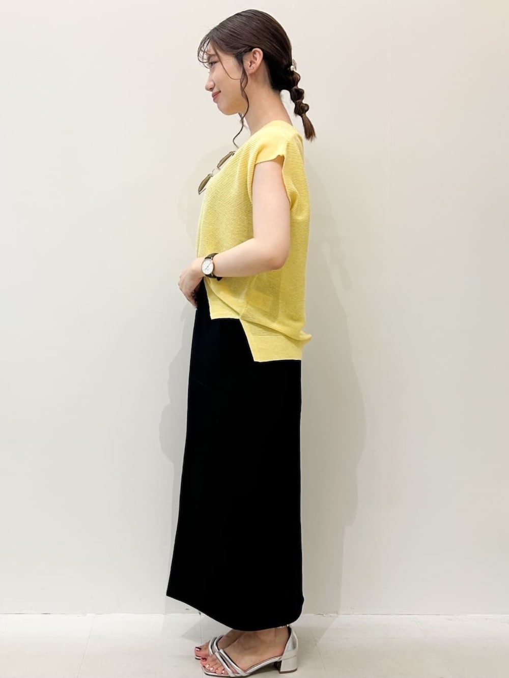 ブラック系のスカート、シルバー系のサンダル、イエロー系のニット/セーターを着用したレディースの夏コーディネートの2枚目の写真