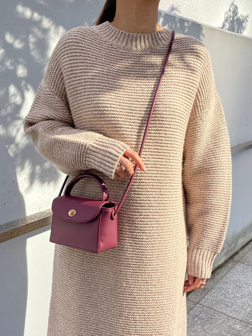 ベージュ系のワンピース、レッド系のショルダーバッグ、ブラウン系のブーツを着用したレディースの冬コーディネートの4枚目の写真