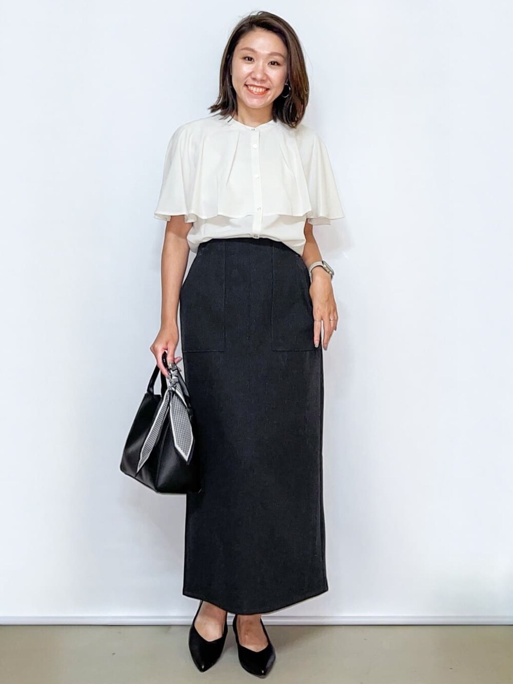 ホワイト系のシャツ/ブラウス、グレー系のスカート、ブラック系のトートバッグを着用したレディースの夏コーディネートの2枚目の写真