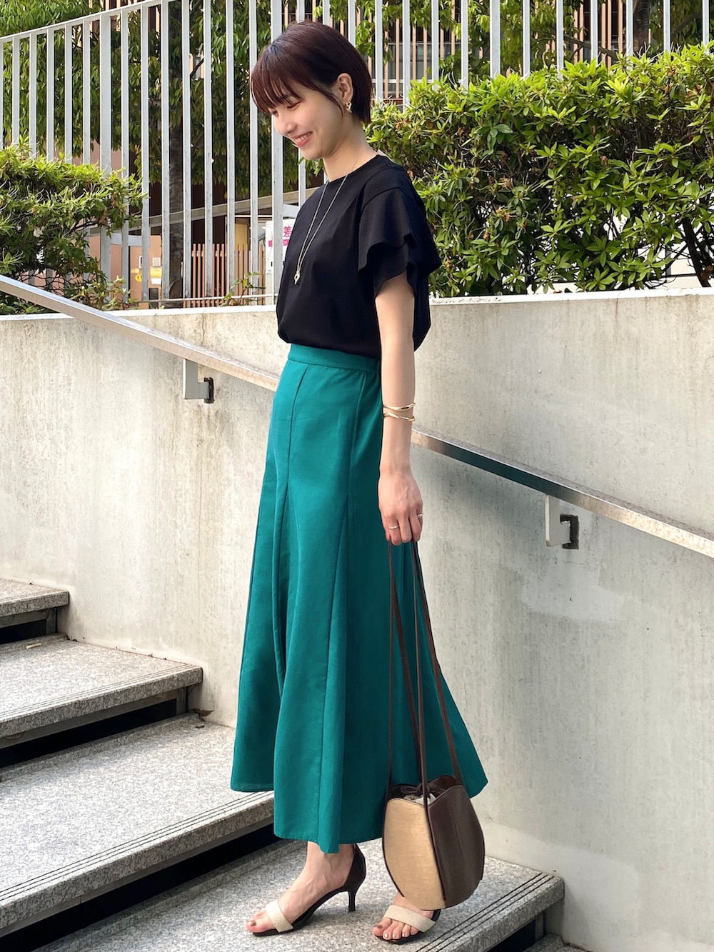 ブラック系のTシャツ/カットソー、グリーン系のスカート、ブラウン系のショルダーバッグを着用したレディースの春コーディネートの2枚目の写真