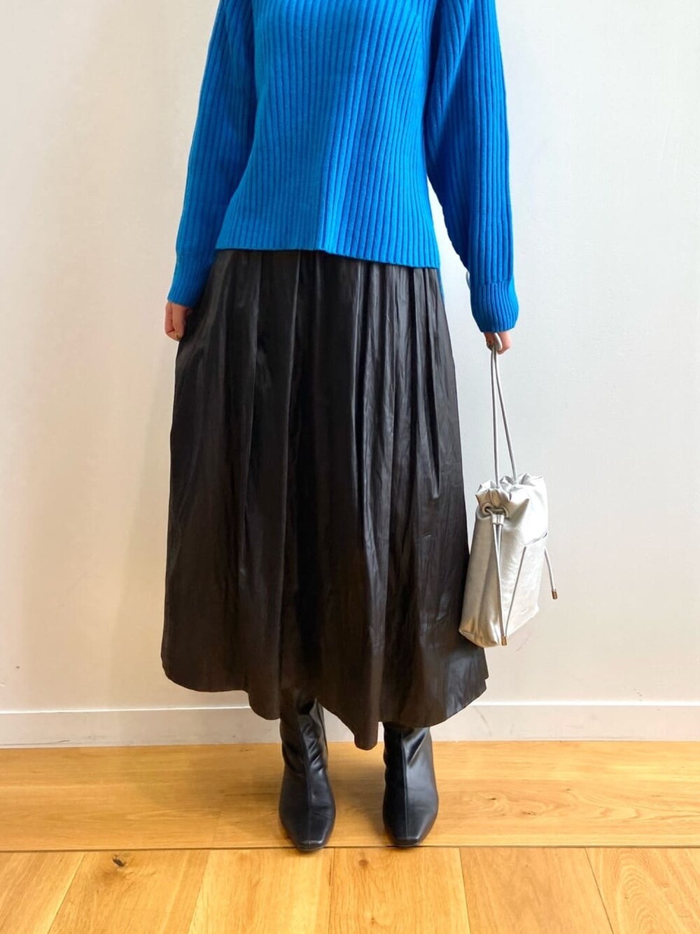 ブルー系のニット/セーター、ブラック系のスカート、ブラック系のブーツを着用したレディースの秋コーディネートの7枚目の写真