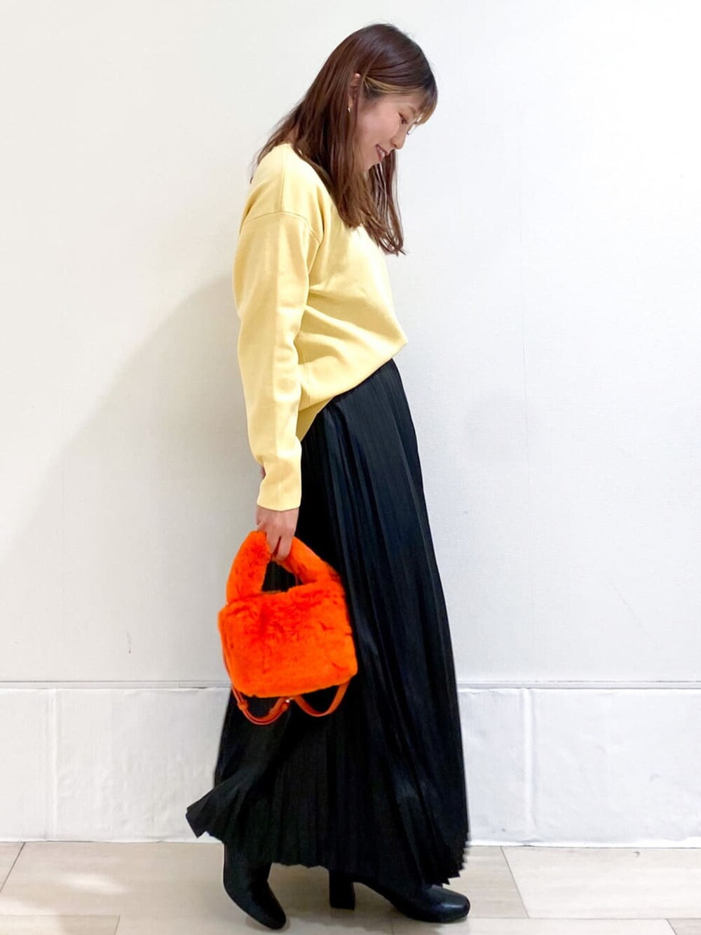 イエロー系のニット/セーター、ブラック系のスカート、オレンジ系のショルダーバッグを着用したレディースの秋コーディネートの4枚目の写真