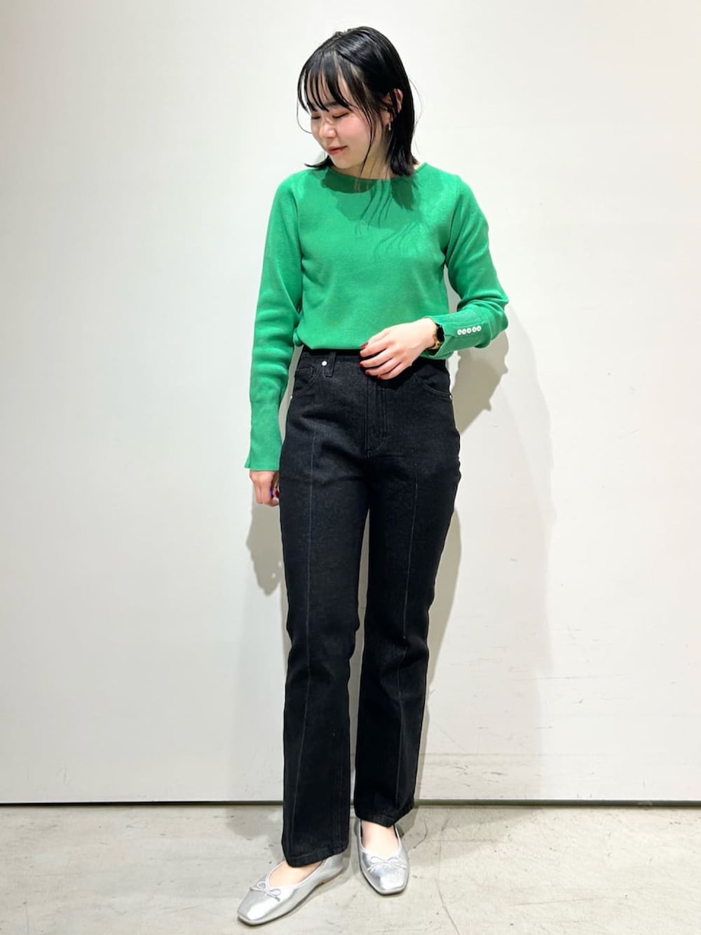 ベージュ系のトレンチコート、グリーン系のニット/セーター、グレー系のデニムパンツを着用したレディースの春コーディネートの2枚目の写真