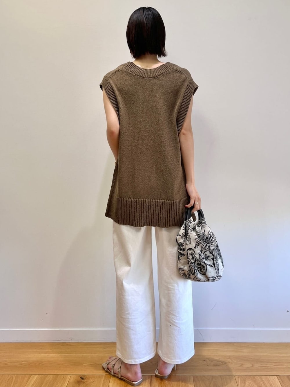 グリーン系のベスト、ホワイト系のハンドバッグ、ホワイト系のデニムパンツを着用したレディースの春コーディネートの3枚目の写真