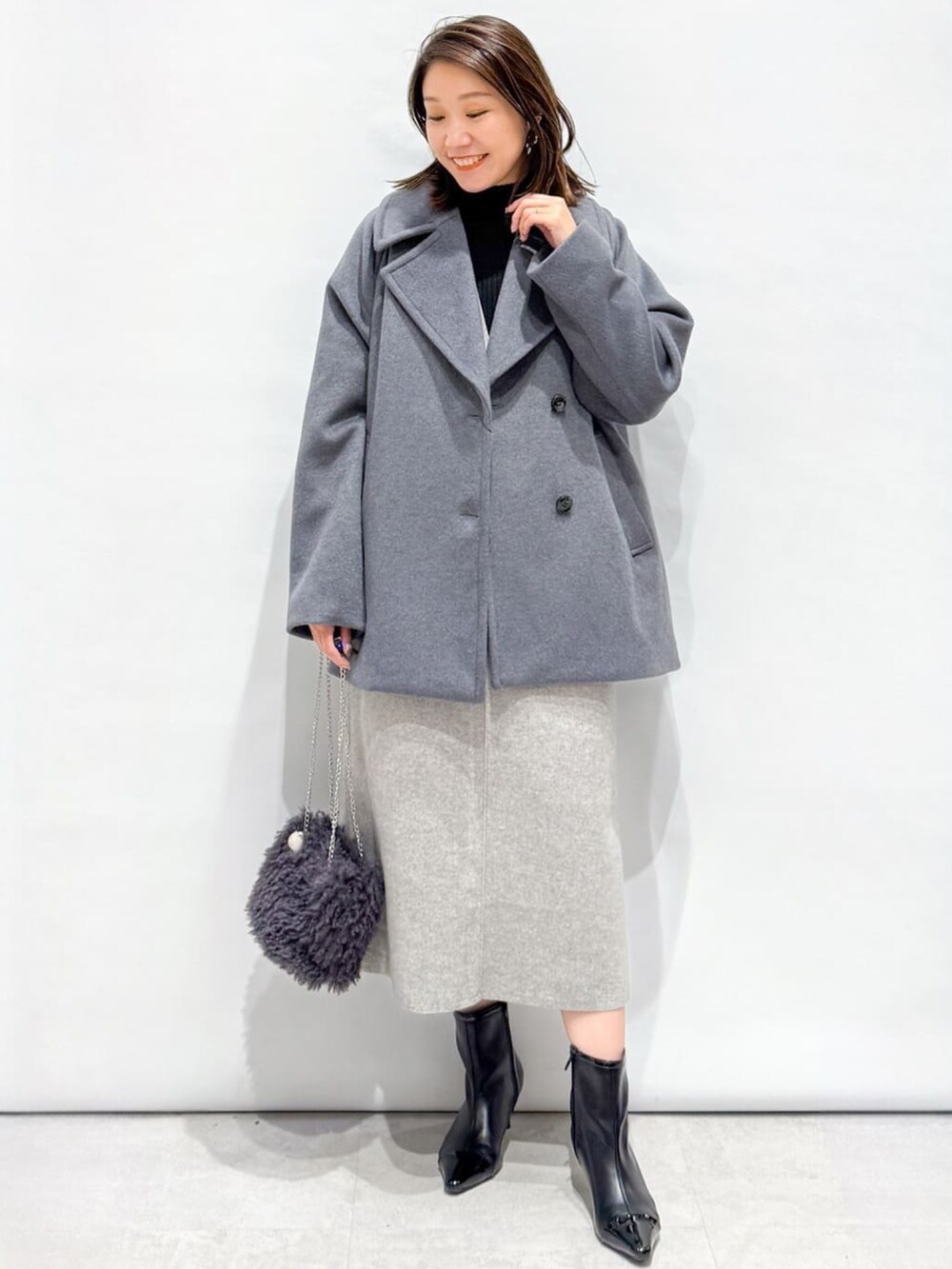 ブラック系のニット/セーター、グレー系のピーコート、グレー系のショルダーバッグを着用したレディースの秋コーディネートの3枚目の写真