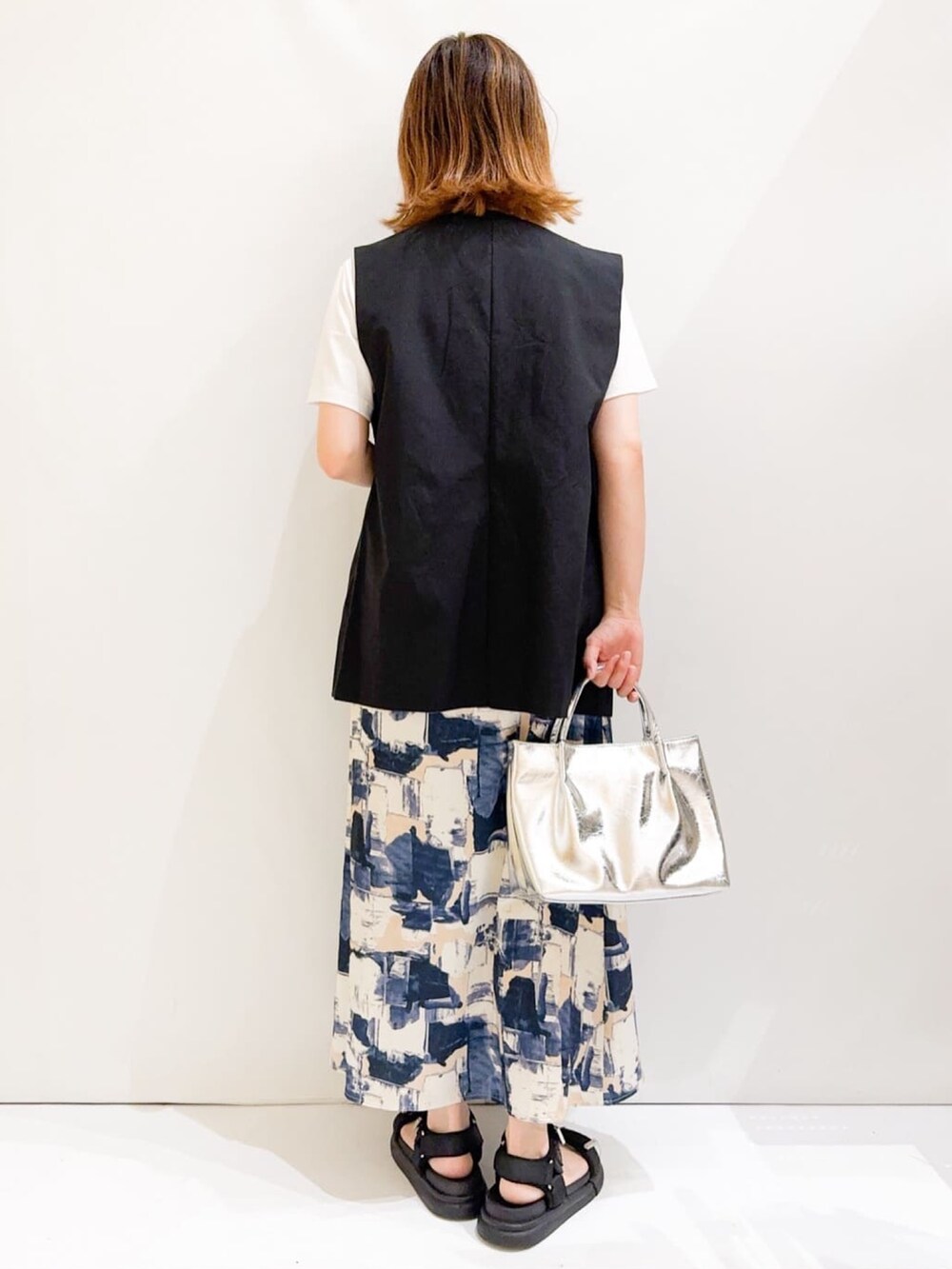 ホワイト系のTシャツ/カットソー、ブラック系のベスト、シルバー系のトートバッグを着用したレディースの夏コーディネートの4枚目の写真