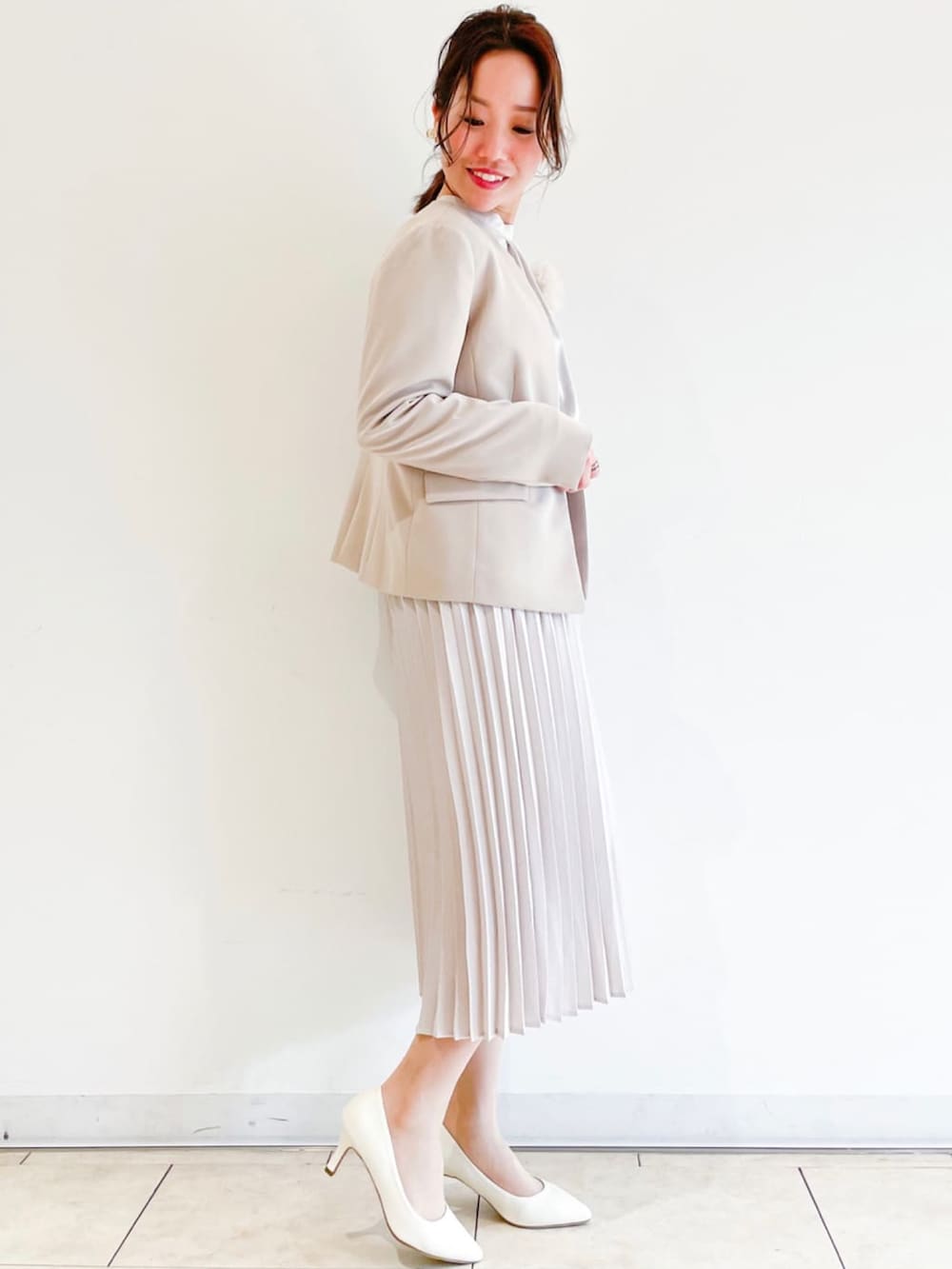 ホワイト系のパンプス、ベージュ系のハンドバッグ、ベージュ系のワンピースを着用したレディースの春コーディネートの2枚目の写真