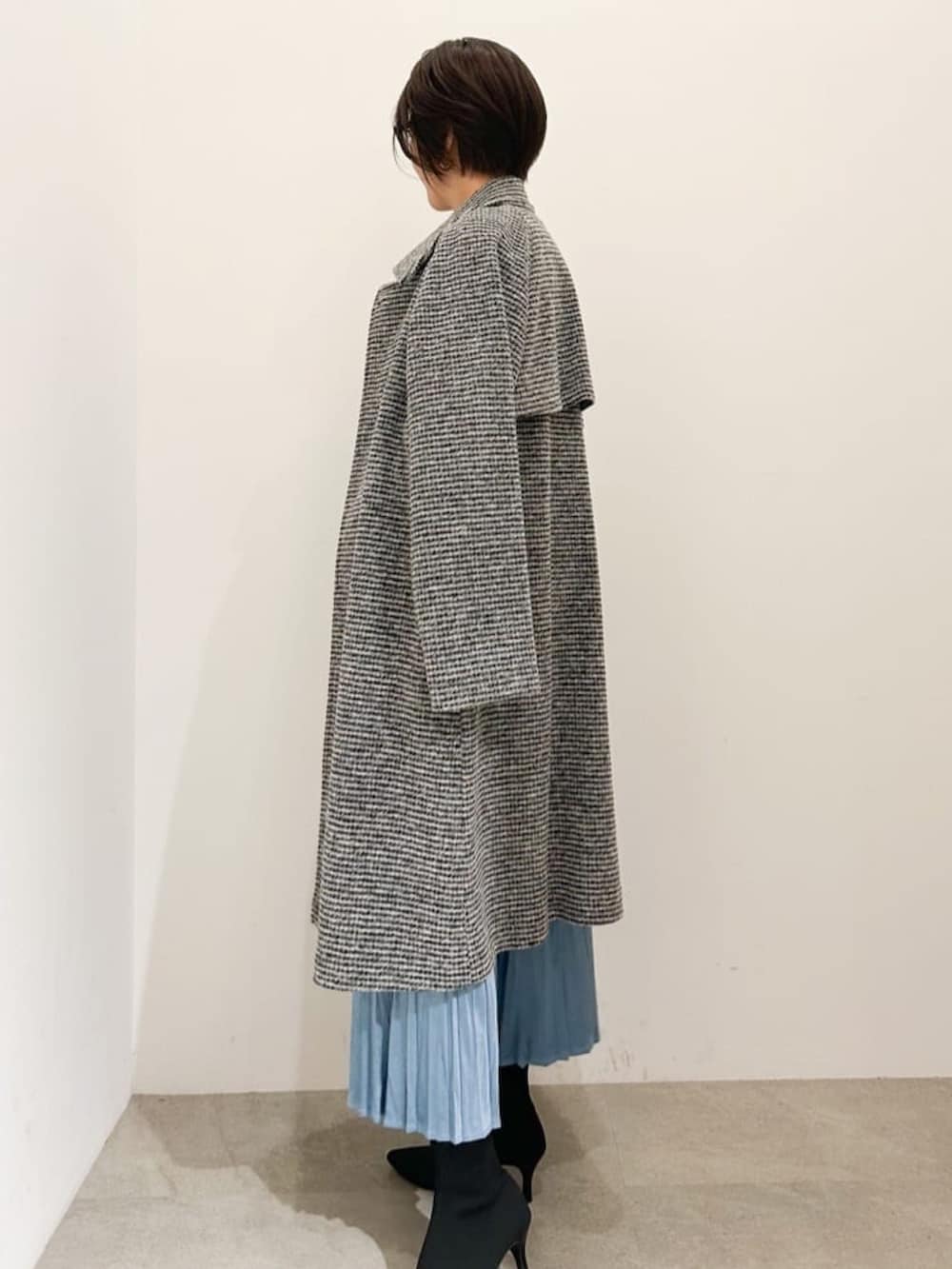 ホワイト系のショルダーバッグ、ホワイト系のチェスターコート、ブラック系のカーディガン/ボレロを着用したレディースの冬コーディネートの2枚目の写真