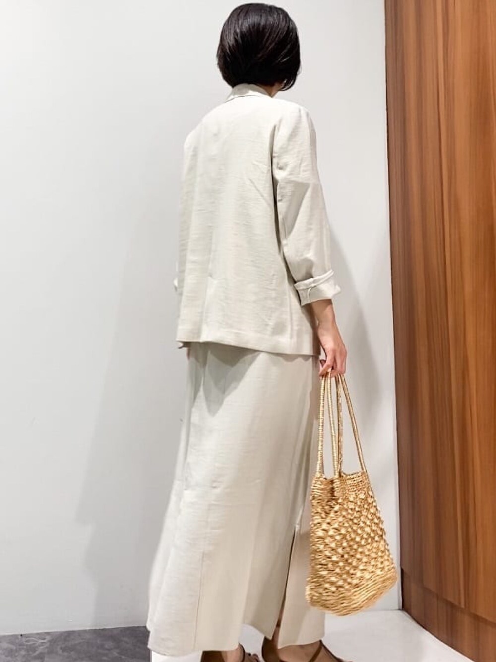 ベージュ系のテーラードジャケット、ベージュ系のスカート、ブラウン系のサンダルを着用したレディースの春コーディネートの3枚目の写真