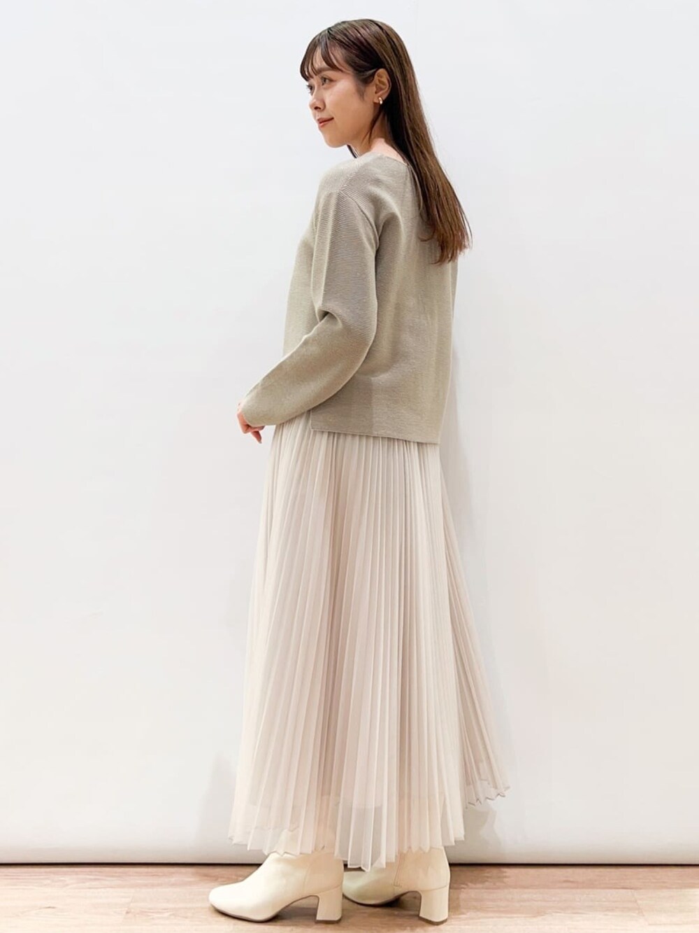 ベージュ系のスカート、ベージュ系のニット/セーター、ホワイト系のブーツを着用したレディースの冬コーディネートの3枚目の写真