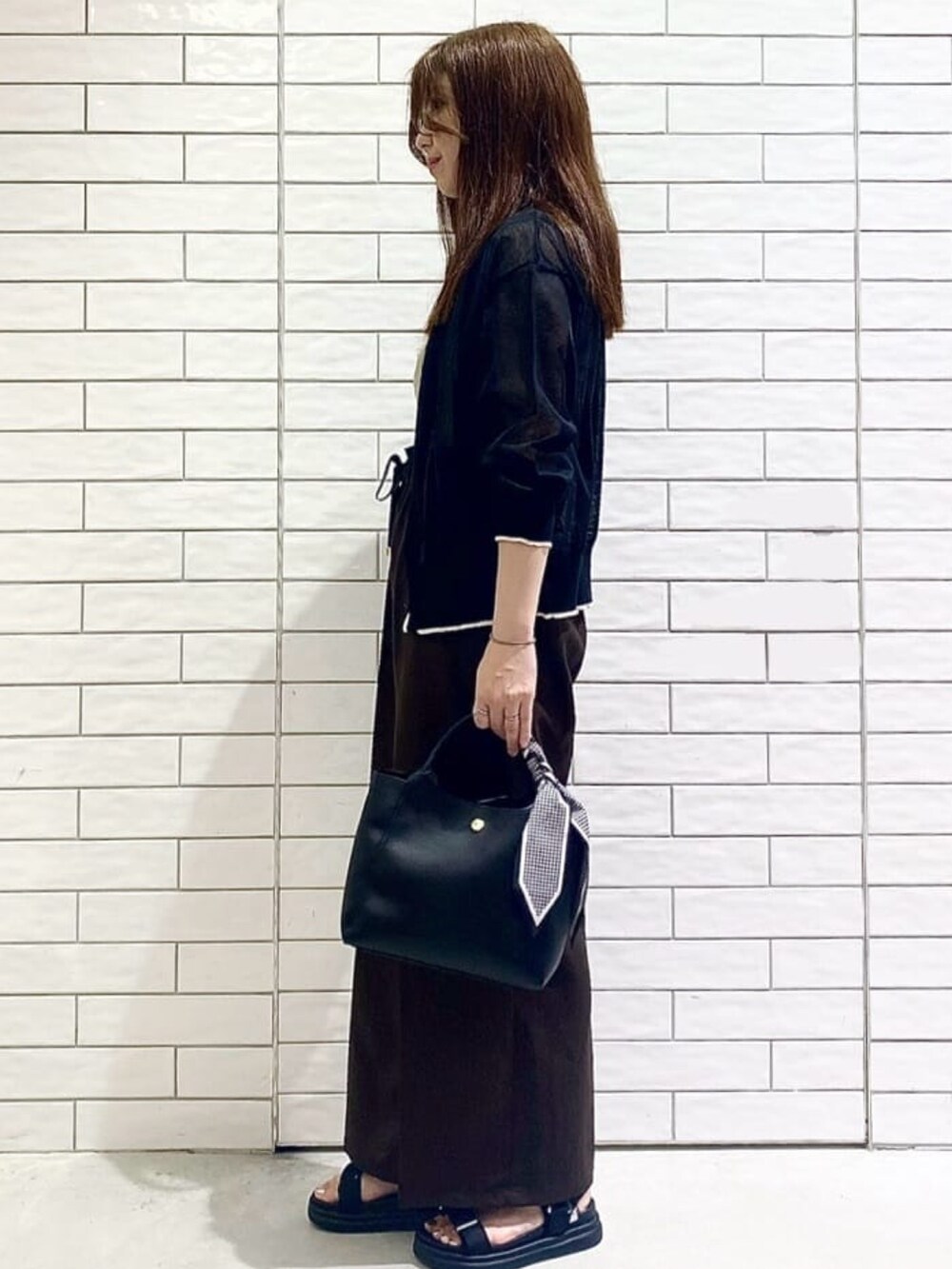 ブラック系のカーディガン/ボレロ、ベージュ系のニット/セーター、ブラック系のトートバッグを着用したレディースの夏コーディネートの2枚目の写真