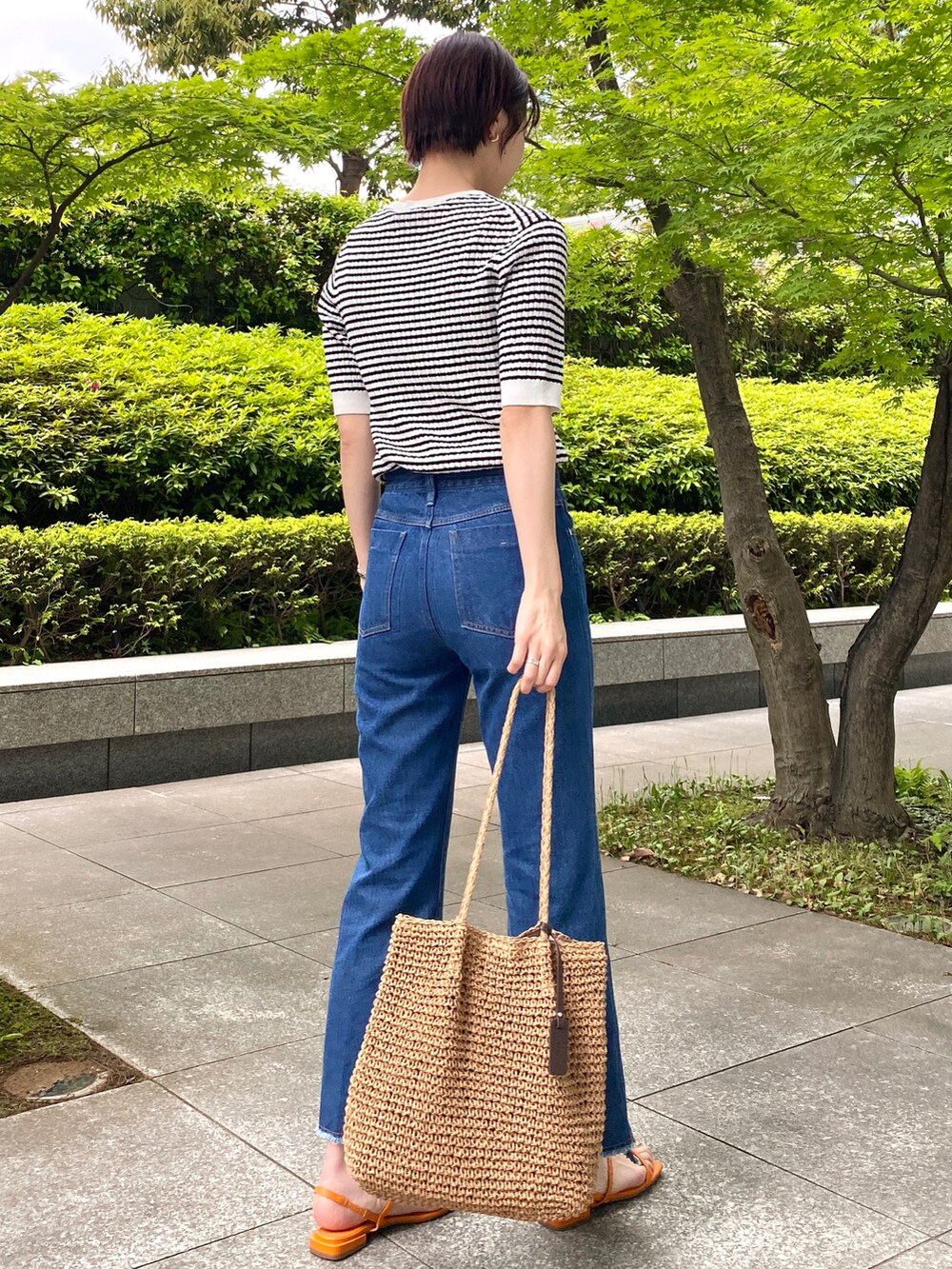 ホワイト系のニット/セーター、ブルー系のデニムパンツ、ベージュ系のトートバッグを着用したレディースの春コーディネートの2枚目の写真