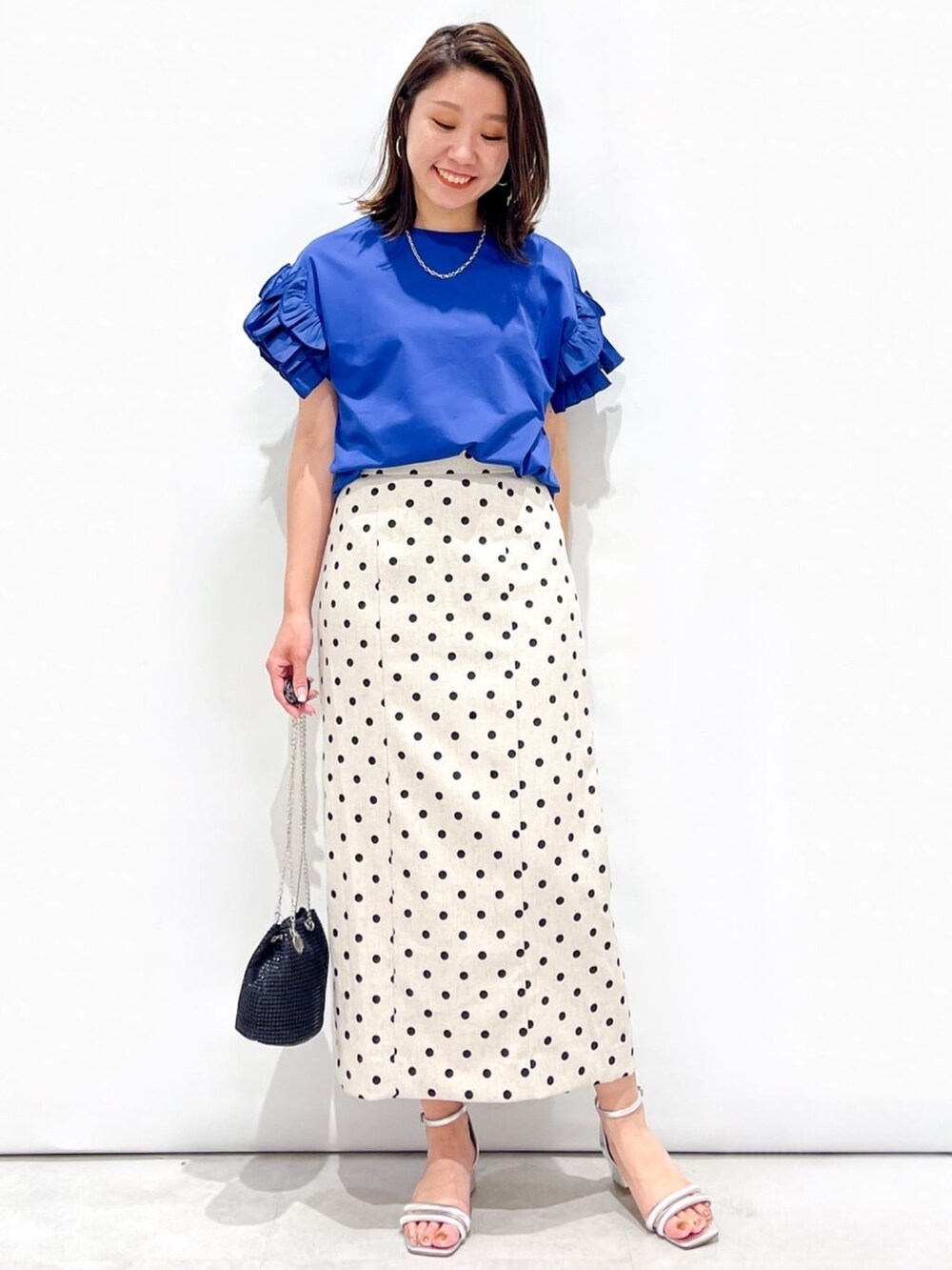 ベージュ系のスカート、ブラック系のショルダーバッグ、シルバー系のサンダルを着用したレディースの夏コーディネートの2枚目の写真