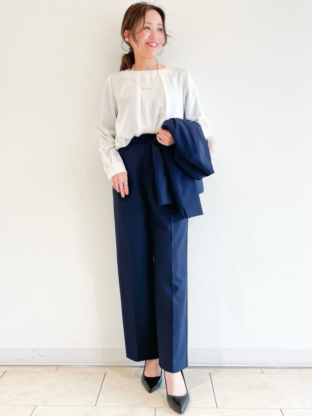 ブラック系のパンプス、ベージュ系のトレンチコート、ブルー系のスーツパンツを着用したレディースの春コーディネートの5枚目の写真