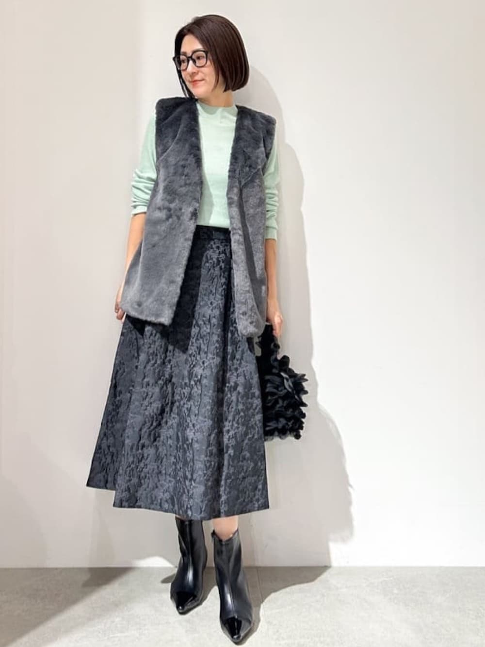 ブラック系のブルゾン、グリーン系のニット/セーター、ブラック系のスカートを着用したレディースの秋コーディネートの4枚目の写真