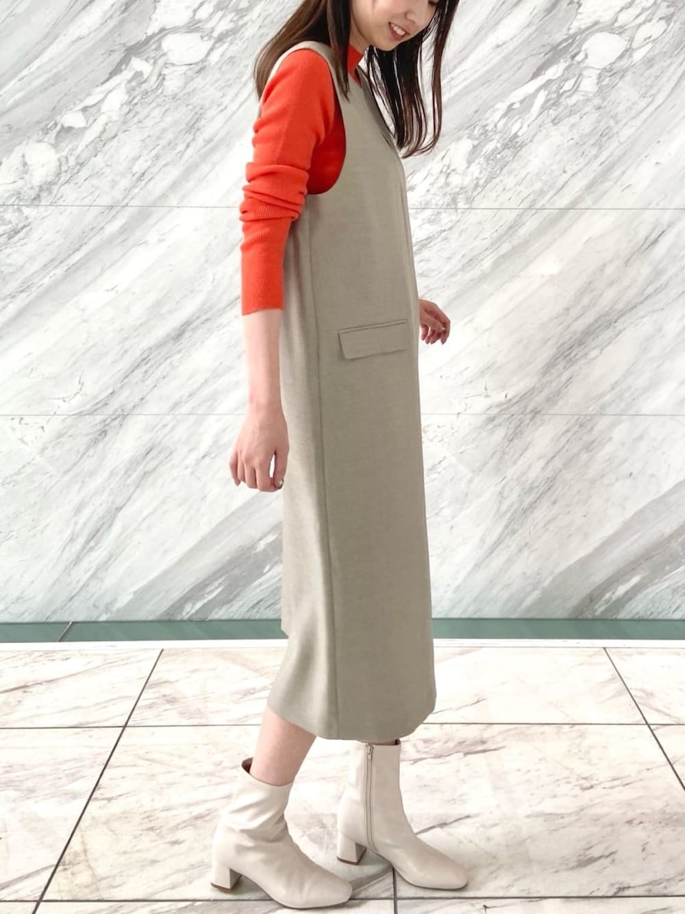 オレンジ系のニット/セーター、ベージュ系のワンピース、ホワイト系のブーツを着用したレディースの秋コーディネートの10枚目の写真