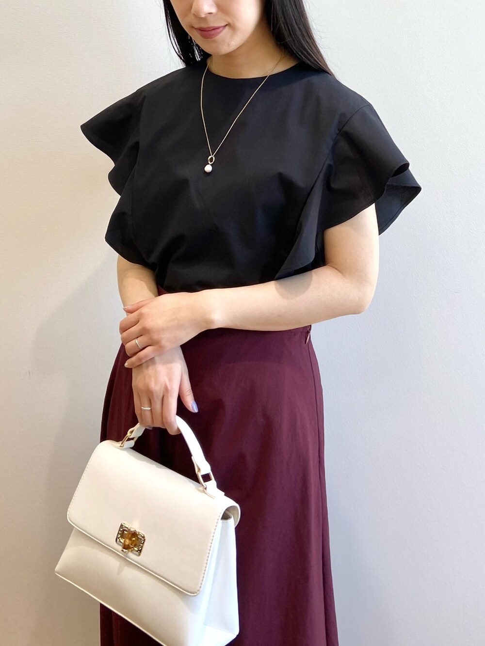 ブラック系のシャツ/ブラウス、レッド系のスカート、ホワイト系のショルダーバッグを着用したレディースの春コーディネートの4枚目の写真