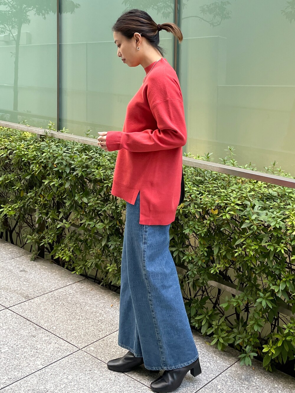 レッド系のニット/セーター、ブルー系のその他パンツ、ブラック系のブーツを着用したレディースの冬コーディネートの2枚目の写真