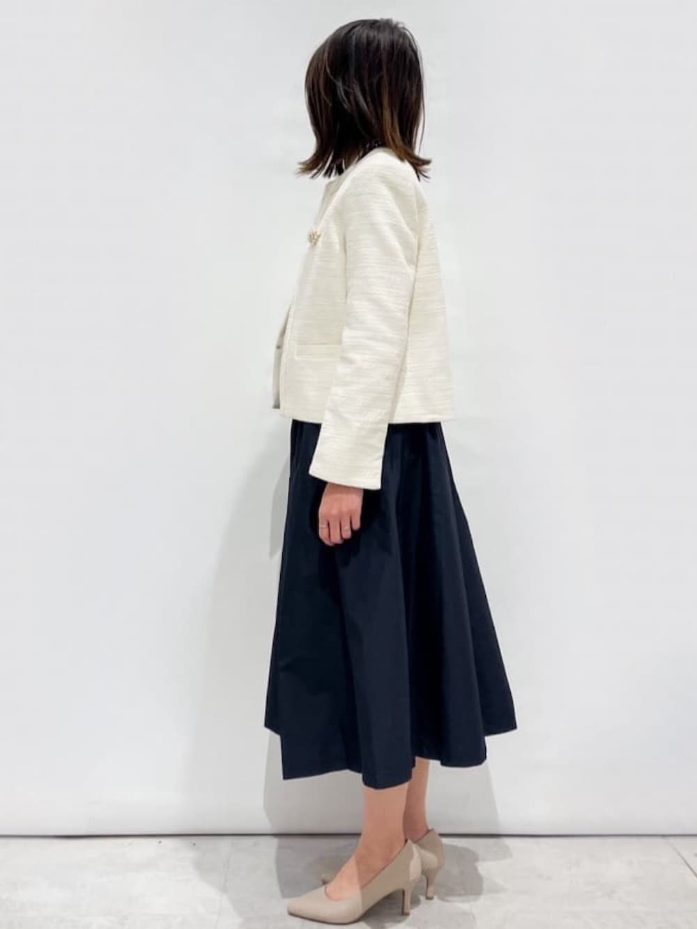 ブルー系のスカート、ホワイト系のノーカラージャケット、ホワイト系のシャツ/ブラウスを着用したレディースの冬コーディネートの2枚目の写真