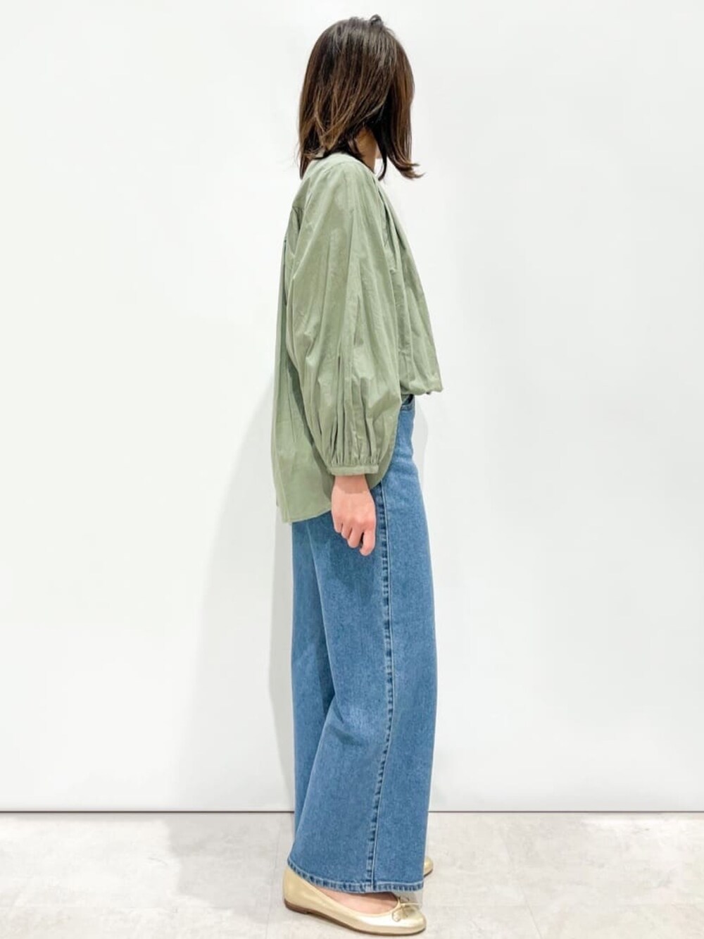 グリーン系のシャツ/ブラウス、ゴールド系のパンプス、ブラック系のトートバッグを着用したレディースの春コーディネートの2枚目の写真