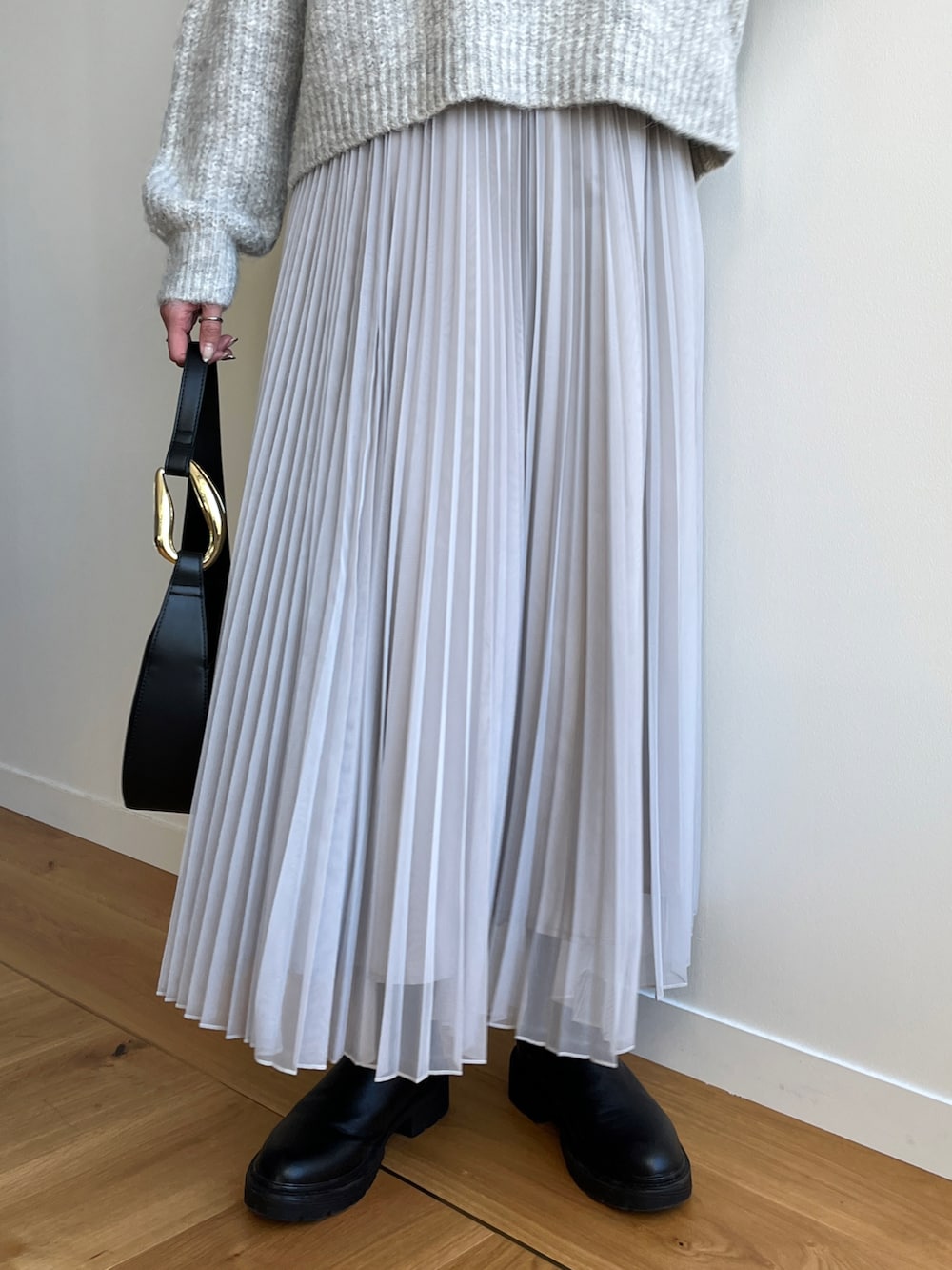 グレー系のニット/セーター、グレー系のスカート、ブラック系のブーツを着用したレディースの冬コーディネートの5枚目の写真