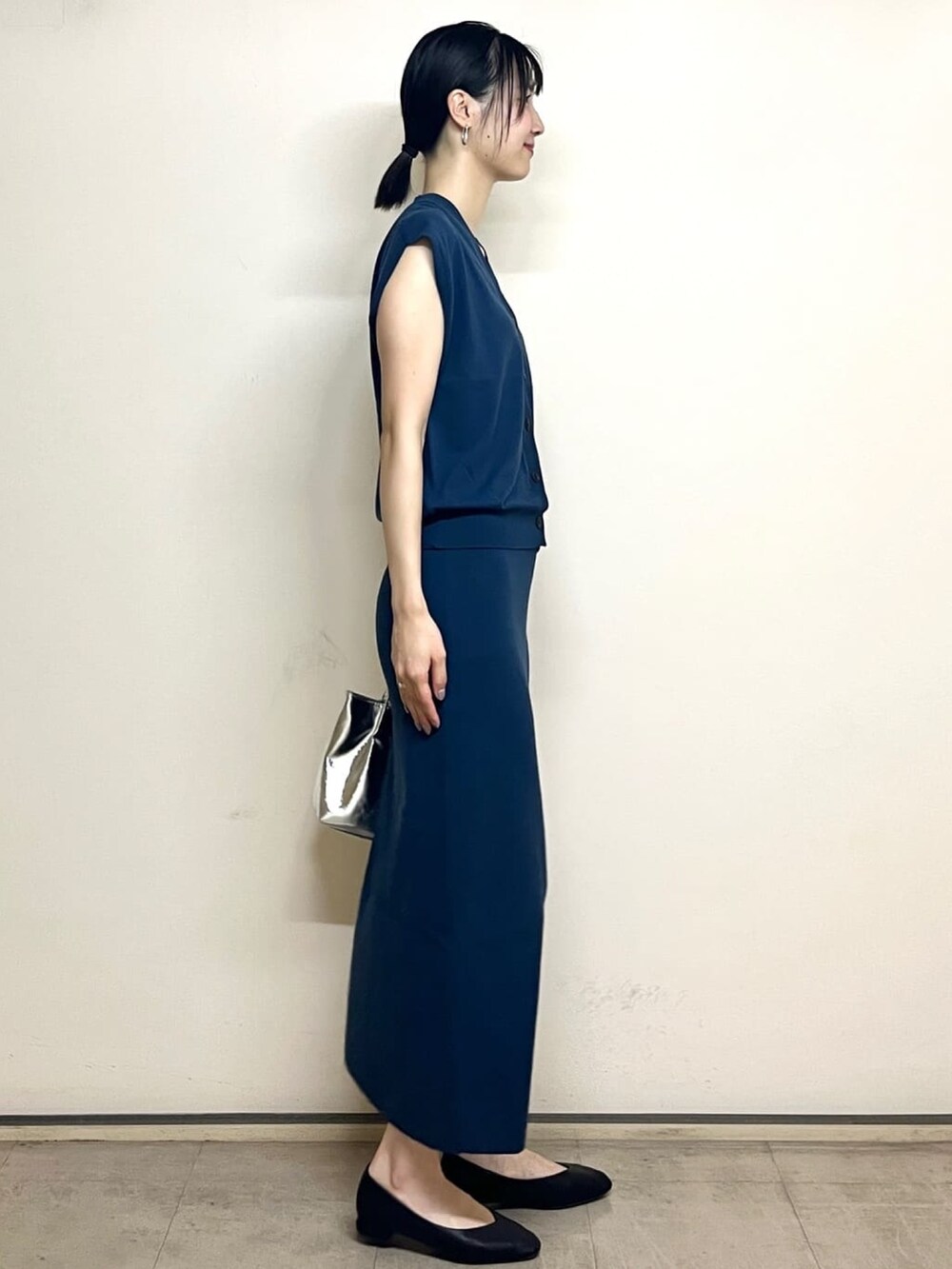 ブルー系のベスト、ブルー系のスカート、シルバー系のトートバッグを着用したレディースの夏コーディネートの3枚目の写真