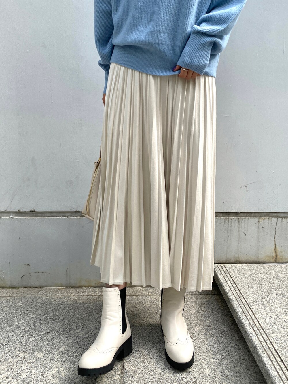 ブルー系のニット/セーター、ホワイト系のスカート、ホワイト系のハンドバッグを着用したレディースの秋コーディネートの5枚目の写真