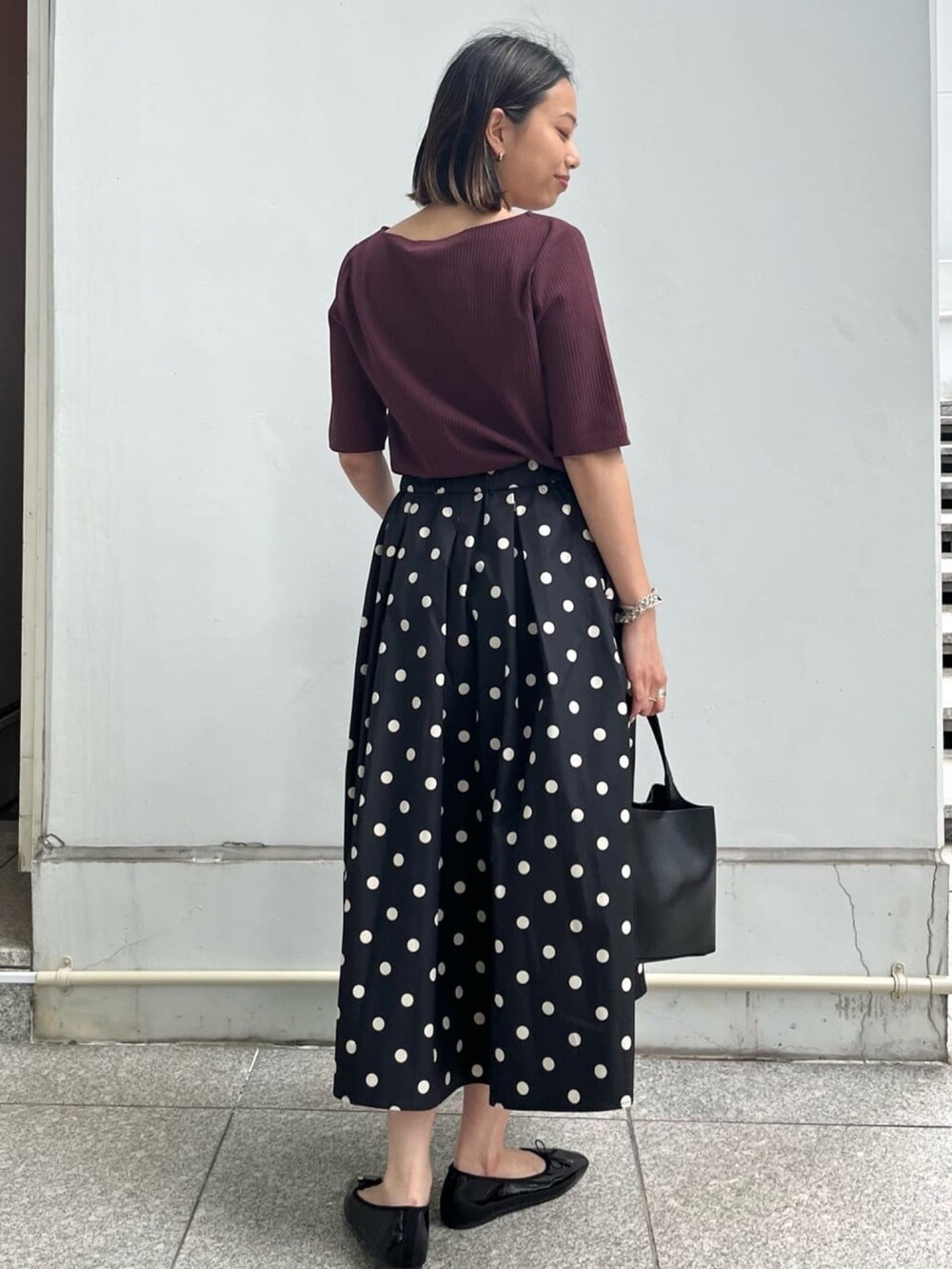 レッド系のTシャツ/カットソー、ブラック系のスカート、ブラック系のパンプスを着用したレディースの夏コーディネートの2枚目の写真