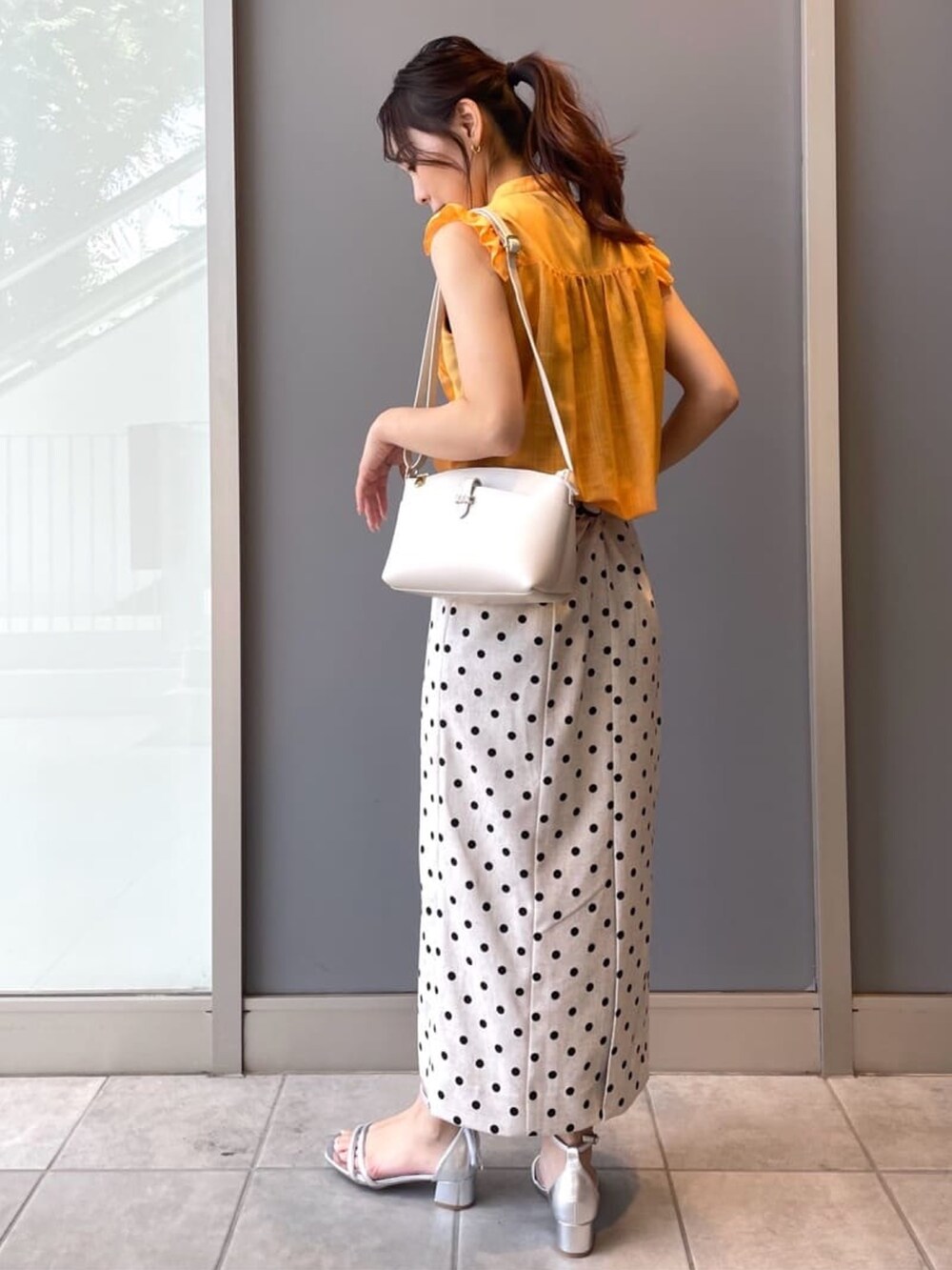 ホワイト系のショルダーバッグ、ベージュ系のスカート、シルバー系のサンダルを着用したレディースの夏コーディネートの3枚目の写真