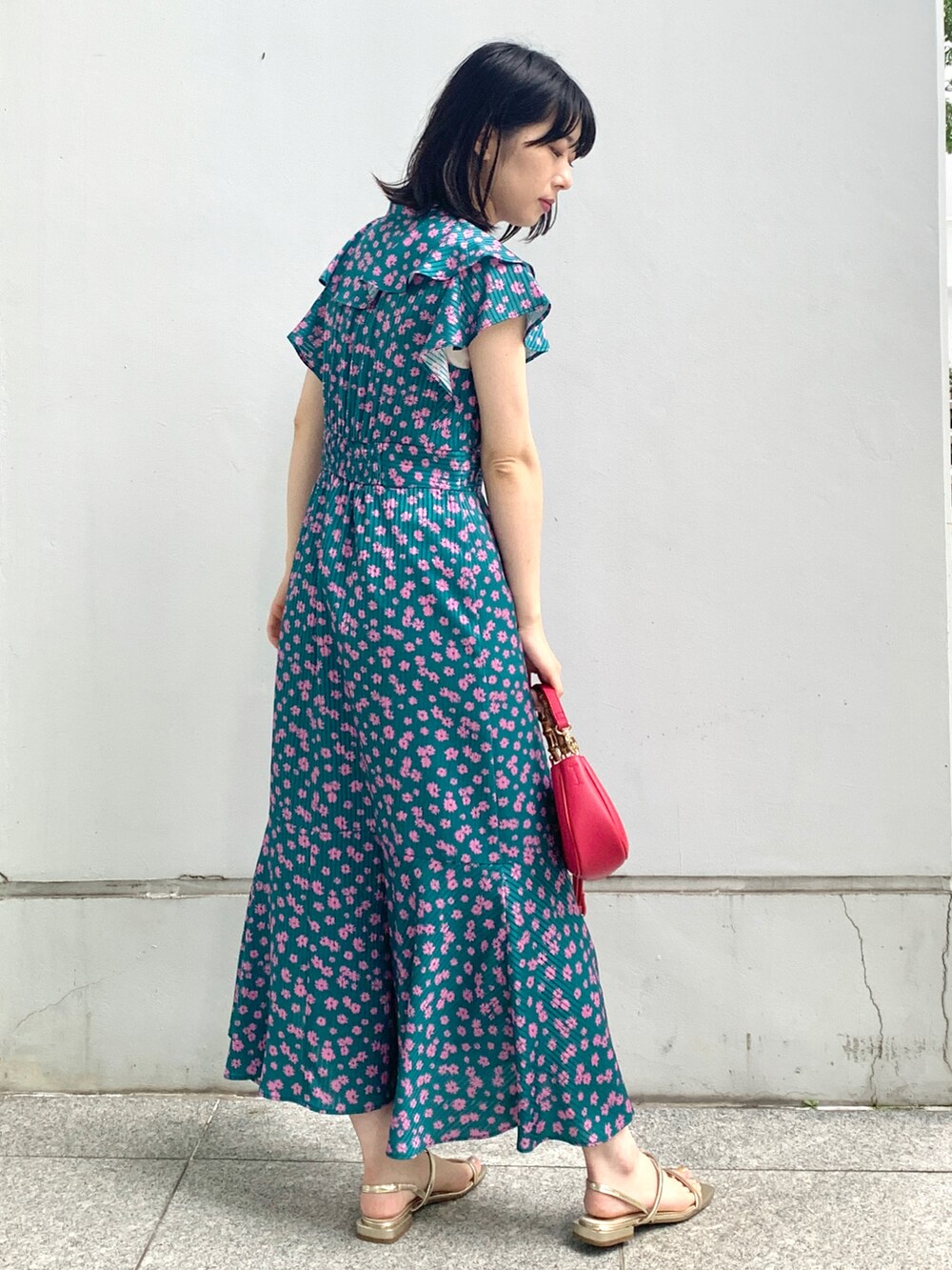 グリーン系のワンピース、ゴールド系のサンダル、ピンク系のショルダーバッグを着用したレディースの夏コーディネートの2枚目の写真