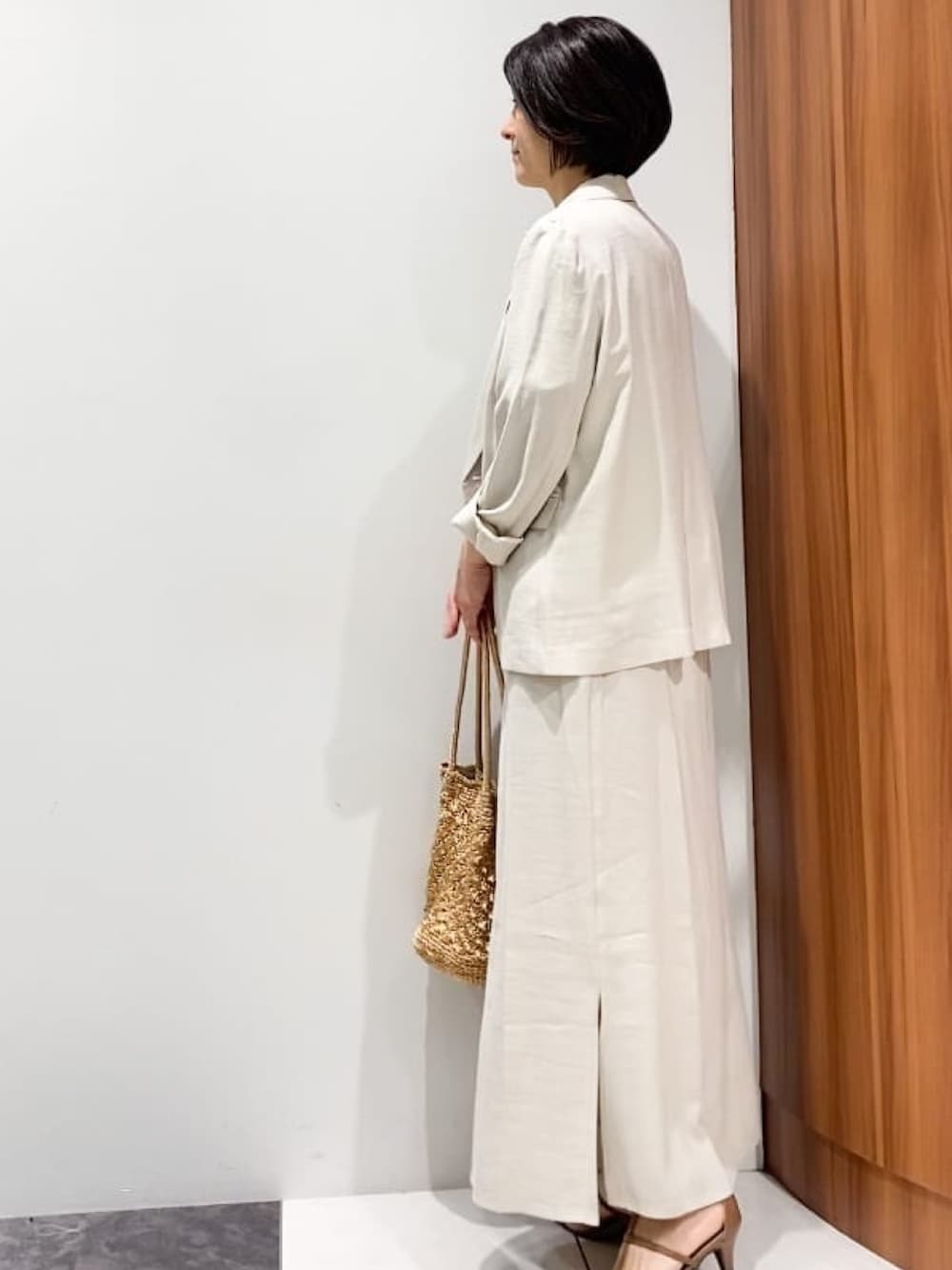 ベージュ系のテーラードジャケット、ベージュ系のスカート、ブラウン系のサンダルを着用したレディースの春コーディネートの2枚目の写真