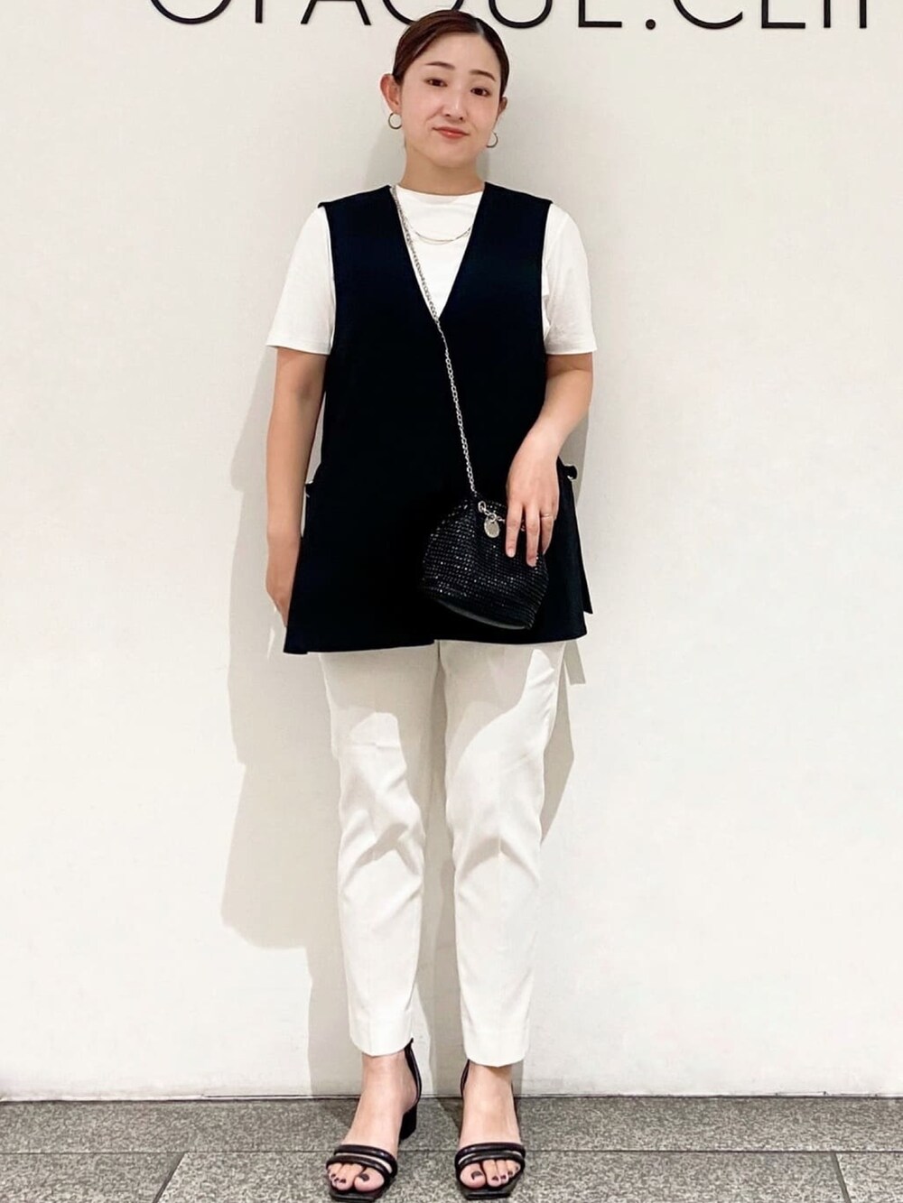 ホワイト系のTシャツ/カットソー、ブラック系のベスト、ブラック系のショルダーバッグを着用したレディースの夏コーディネートの2枚目の写真