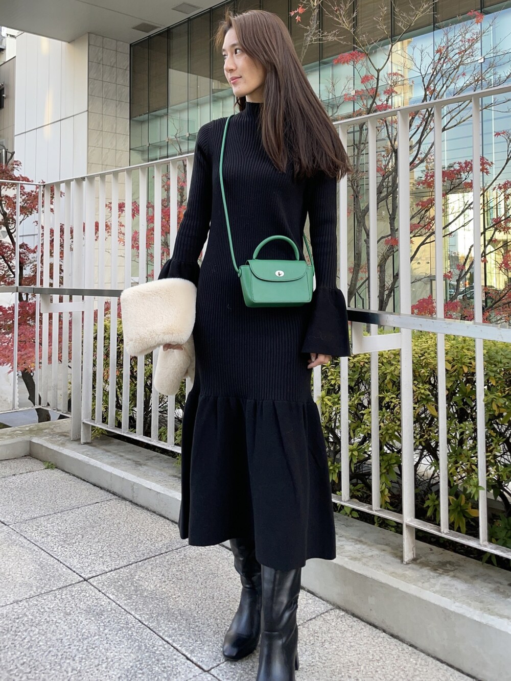 ブラック系のワンピース、ブラック系のブーツ、グリーン系のショルダーバッグを着用したレディースの冬コーディネートの2枚目の写真