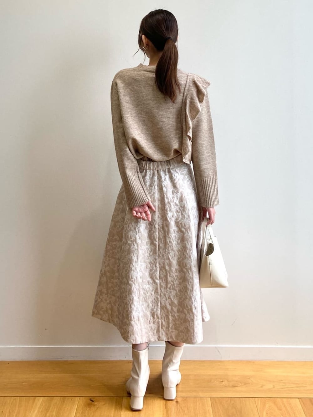 ベージュ系のニット/セーター、ホワイト系のトートバッグ、ベージュ系のスカートを着用したレディースの秋コーディネートの3枚目の写真